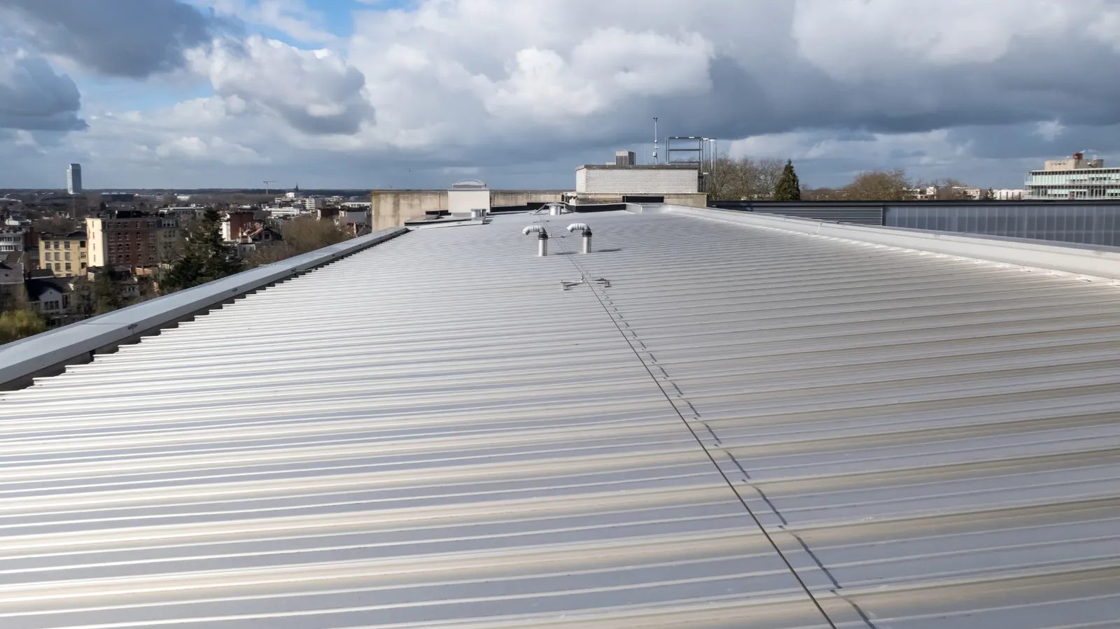 Commercial building with a long metal roof overlooking a city skyline
